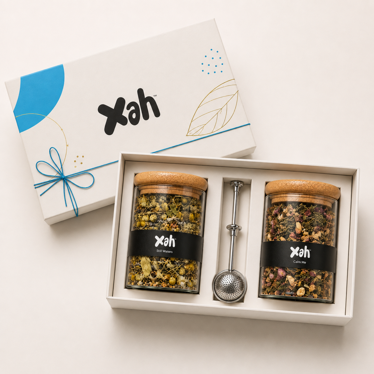 Xah festive tea gift box with two glass jars of whole-leaf tea and a tea strainer